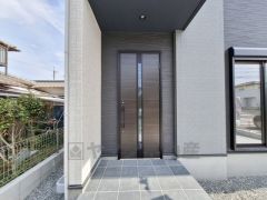 玄関はシンプルで洗練されたデザインが特徴です。落ち着いたカラーの玄関ドアが外観と調和しています。十分なスペースが確保されているアプローチ部分は屋根付きで、雨の日でも安心です。