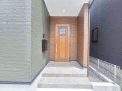 落ち着いた印象の玄関デザインで、ウッド調のドアが温かみを感じさせます。玄関アプローチがゆったりと設けられてて、モダンな外壁が目を引きます。シンプルな外観でメンテナンスもしやすそうです。