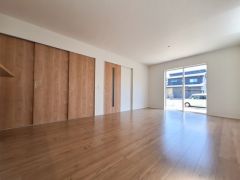 大きな窓から光が差し込む明るいリビングです。ナチュラルな木目調の床と扉が空間を引き立てます。ゆとりのある広さで家具の配置も自由自在です。収納スペースも豊富にありすっきりとした印象です。