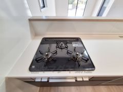 三口のガスコンロが設置されており調理スペースがしっかりと確保されています。清潔感のあるキッチンでお手入れも簡単です。作業動線を考えた配置が魅力的です。