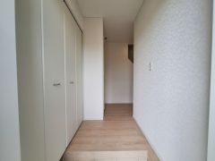 シンプルなデザインの玄関はすっきりとした印象を与えます。ホワイト系の扉や壁が空間をより広く感じさせます。収納スペースが備え付けられており使い勝手にも配慮されています。