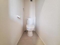 コンパクトにまとめられたトイレスペースです。シンプルな壁紙と明るい床材が圧迫感を感じさせません。ペーパーホルダーなど必要な設備が設置されています。