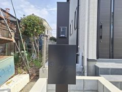 宅配ボックスとインターホンが設置されています。シンプルなブラックのデザインが建物と調和しています。玄関周りもすっきりとした印象です。