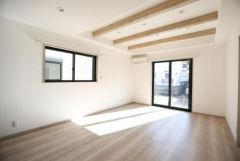 明るい光が差し込むリビングは天井の梁がアクセントとなっています。ナチュラルなフローリングが空間を引き立てます。大型の窓とバルコニーへのアクセスも便利です。