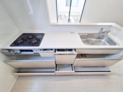 キッチンは収納力のある引き出しが充実しています。使いやすいコンロとシンクが横並びで家事のしやすさが感じられます。ナチュラルな床色が清潔感を演出しています。