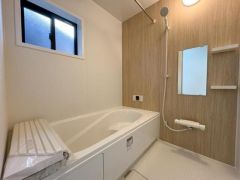 明るい照明と木目調の壁が特徴的なバスルームです。窓付きで換気も簡単です。