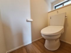 明るい印象のトイレです。壁や床の色合いが落ち着いていて清潔感が感じられます。窓があるため換気もしやすくなっています。スペースにゆとりが確保されています。シンプルなデザインで使いやすい印象です。