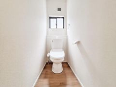 コンパクトな空間に設置されたトイレはシンプルな内装が印象的です。 小窓があり自然光を取り入れることができます。 壁や床の色合いが落ち着いていてすっきりとした印象です。