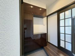 玄関には収納力のあるシューズボックスが設置されておりすっきりとした印象です。落ち着いた色味のフローリングと建具が調和し清潔感のある空間です。ドアにはガラスが施されており採光性にも配慮されています。