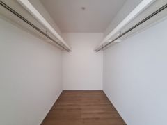 広々とした収納スペースが備えられており整理整頓しやすい仕様です。シンプルな内装で使いやすさが感じられます。両側に設置されたハンガーパイプが便利です。木目調の床が落ち着いた雰囲気を演出します。