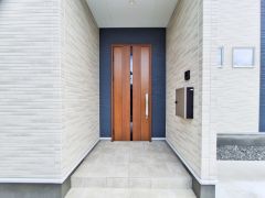 落ち着いた色合いの外壁と木目調の玄関ドアが調和した玄関です。ゆったりとしたアプローチがあり玄関まわりもすっきりとした印象です。直線的なデザインがシンプルで飽きのこない魅力を感じさせます。