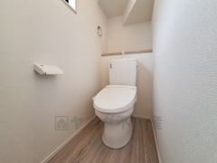 清潔感のあるトイレ空間です。シンプルなデザインで落ち着いた印象を与えます。壁や床も明るい色合いで開放的な雰囲気が感じられます。ペーパーホルダーやタオル掛けが使いやすい位置に配置されています。