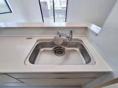 すっきりとしたデザインのシンクが印象的です。広々としたカウンターで作業もはかどります。シンプルな色合いが空間を明るく見せています。窓からの自然光でキッチンがより開放的になります。