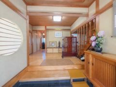 玄関が広々としており木の温もりを感じるデザインです。和風の丸窓や飾り棚が目を引きます。
