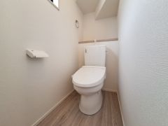 清潔感のあるトイレ空間です。シンプルなデザインで落ち着いた印象を与えます。壁や床も明るい色合いで開放的な雰囲気が感じられます。ペーパーホルダーやタオル掛けが使いやすい位置に配置されています。