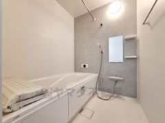 明るく清潔感のあるバスルームです。浴槽はゆったりとした造りでリラックスできる空間です。壁面には収納棚や鏡があり使い勝手が良い仕様です。浴室乾燥機用の物干しパイプも備えられています。