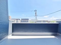 広々としたバルコニーでゆったりとした空間が確保されています。明るい日差しが差し込む設計です。高めの手すりで安心感があります。周囲の景観もすっきりとしています。屋外の開放感を感じられます。