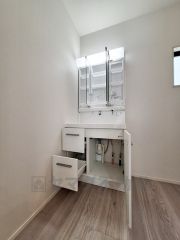 洗面台は収納スペースが充実しており使い勝手の良いデザインです。三面鏡が備わっているのでお手入れも便利に行えます。明るい空間で清潔感のある洗面所です。