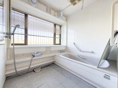 大きな窓から光が差し込む明るいバスルームです。手すり付きで使い勝手にも配慮されています。