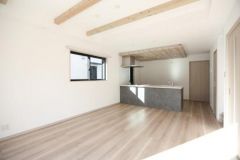 明るい光が差し込むリビングはナチュラルな木目調の床と天井の梁がアクセントです。開放感のある空間でキッチンとの一体感が魅力となっています。窓からの自然光が印象的で室内全体に清潔感があります。